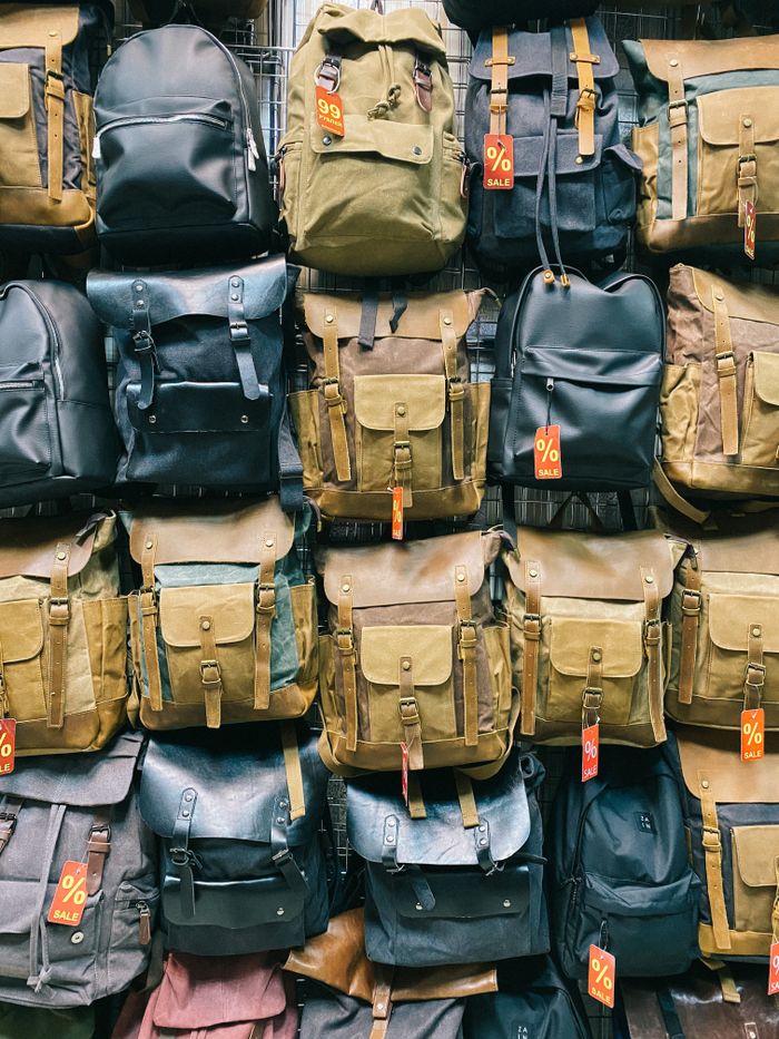 A variety of backpacks on sale with promotional tags in a retail setting.