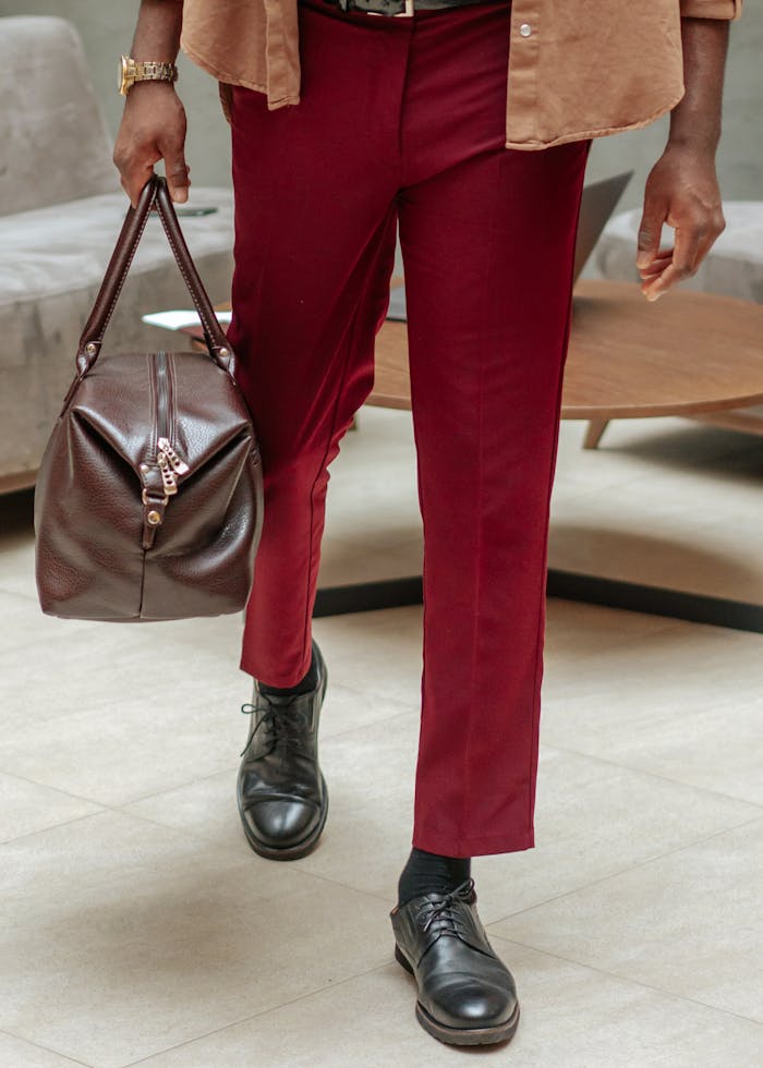 About Man in red pants with leather bag and shoes in stylish setting. Perfect for fashion themes.